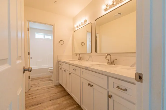a spacious bathroom with a double vanity sink a mirror and a shower