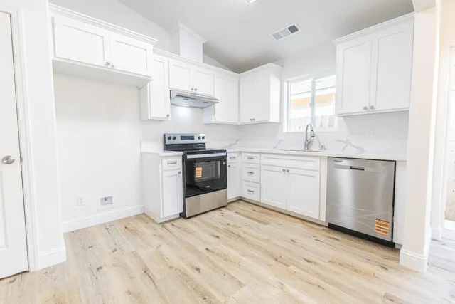 a kitchen with stainless steel appliances granite countertop a stove a sink and white cabinets