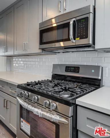 a kitchen with stainless steel appliances granite countertop white cabinets and black stove top oven with granite countertops