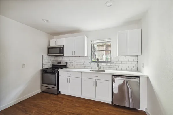 a kitchen with stainless steel appliances granite countertop a sink stove and wooden floor