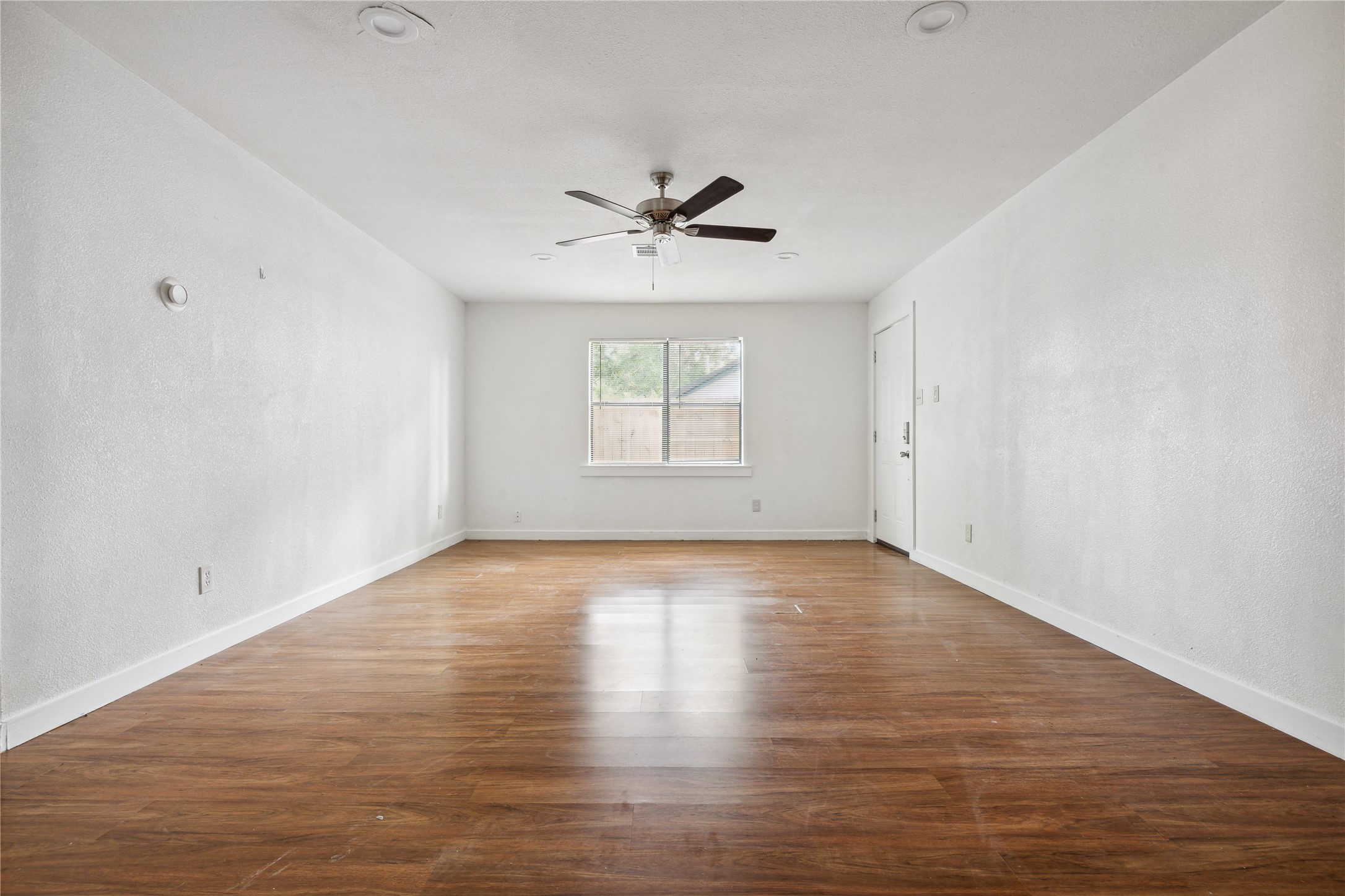 4210 Delhi Street, Unit 1/2 Houston, TX 77022 - Photo 6 of 8 an empty room with wooden floor chandelier fan and windows