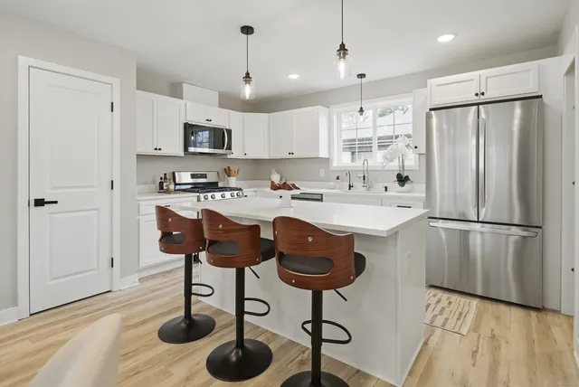 a kitchen with stainless steel appliances granite countertop a sink a stove a refrigerator cabinets and chairs