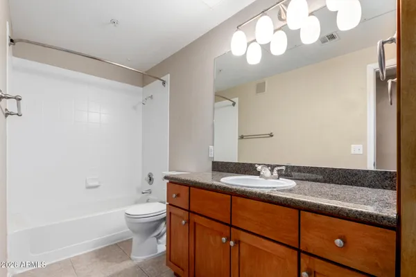 a bathroom with a granite countertop sink a toilet a mirror and shower
