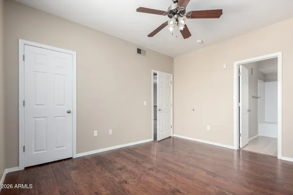 an empty room with wooden floor ceiling fan and windows