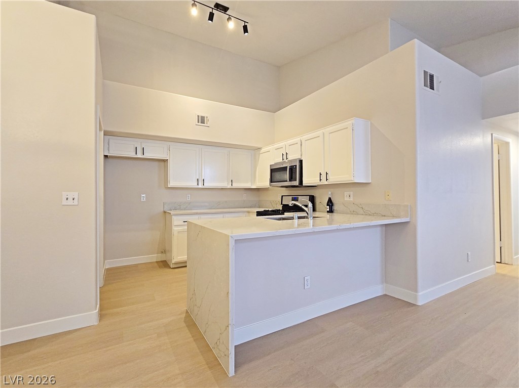 5370 Runningbrook Road Las Vegas, NV 89120 - Photo 9 of 30 Culinary aspirations come alive in this kitchen featuring abundant white cabinetry and sleek stone countertops.