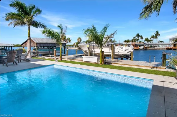 a view of a swimming pool with a lawn chairs under palm trees
