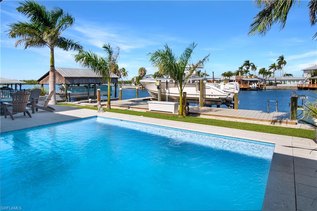 a view of a swimming pool with a lawn chairs under palm trees