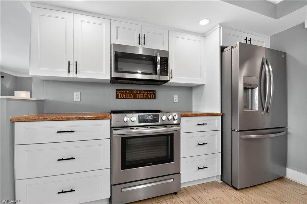 190 Tahiti Circle Naples, FL 34113 - Photo 9 of 32 a kitchen with white cabinets and stainless steel appliances