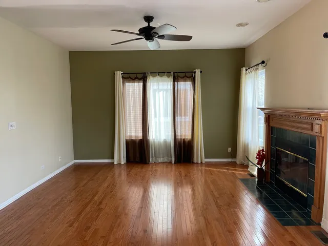 an empty room with wooden floor fireplace and windows