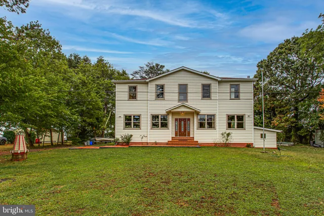a front view of a house with a garden and trees