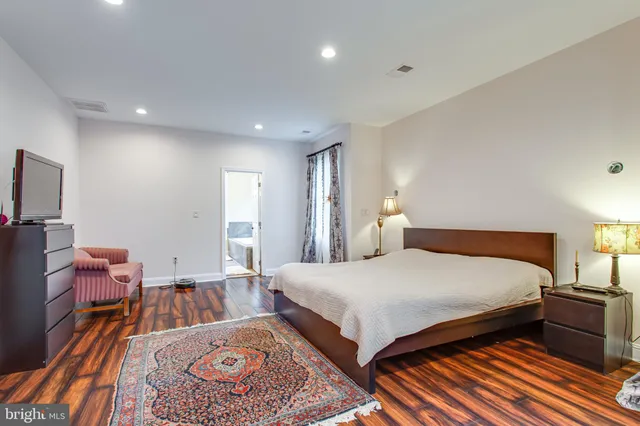 a spacious bedroom with a bed and wooden floor