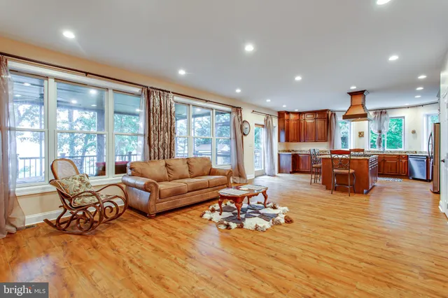 a kitchen with stainless steel appliances kitchen island granite countertop a refrigerator a stove top oven a sink and a dining table with wooden floor