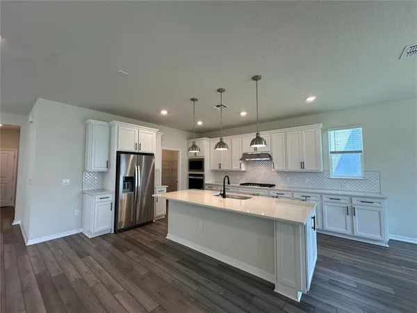 a large kitchen with stainless steel appliances kitchen island a stove a refrigerator a sink dishwasher and a oven with cabinets