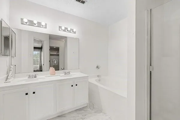 a bathroom with a double vanity sink a mirror and a bathtub