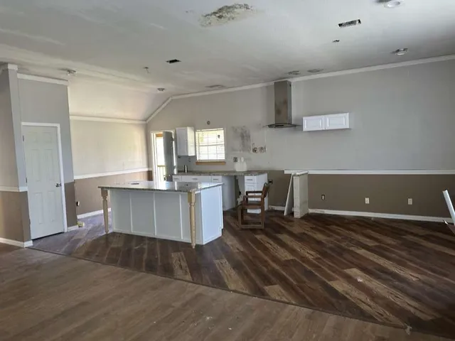 a large kitchen with cabinets chairs and wooden floor