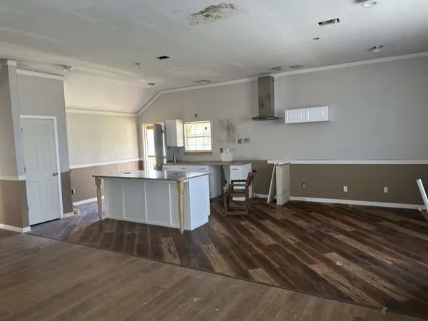 a large kitchen with cabinets chairs and wooden floor