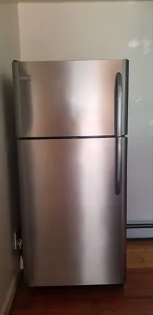 a view of a refrigerator in kitchen and an empty room