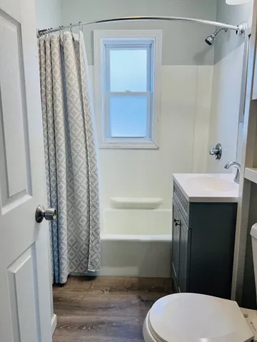 a bathroom with a sink a toilet a window and tub