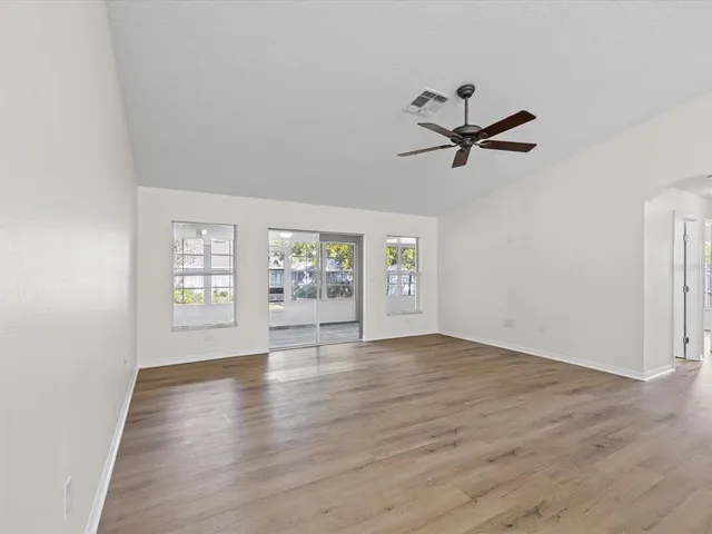 an empty room with wooden floor and windows