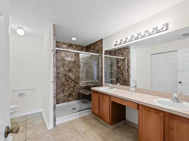 a bathroom with a double vanity sink toilet mirror and bathtub