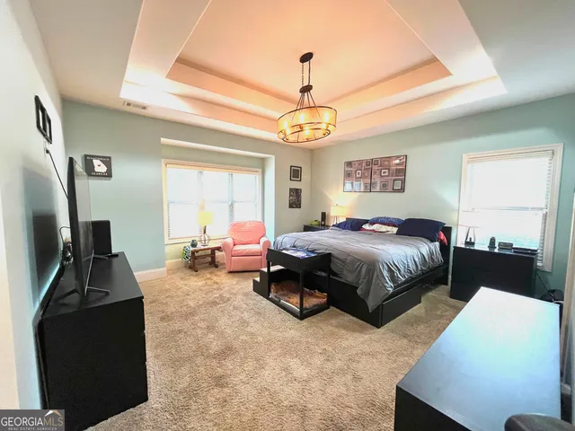 a spacious bedroom with a bed and a chandelier