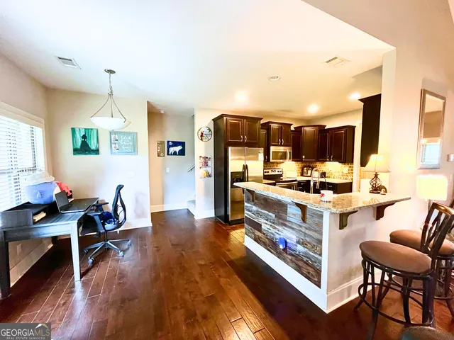 a living room with stainless steel appliances kitchen island granite countertop furniture and a wooden floor