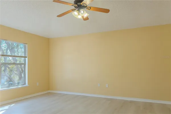 an empty room with windows and fan