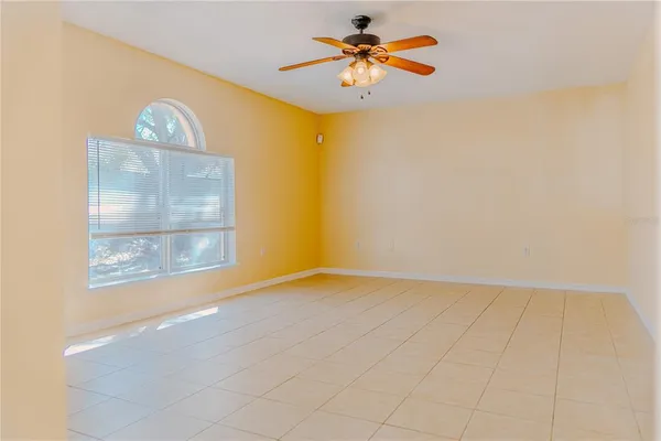 an empty room with a window and a chandelier fan