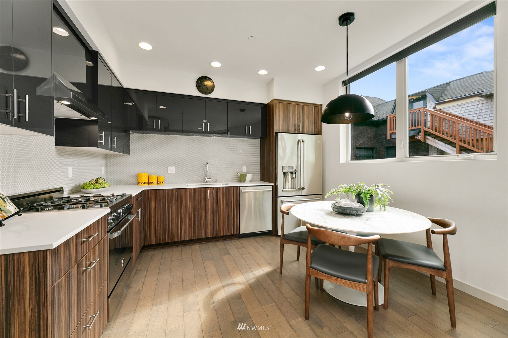 327 West Olympic Place, Unit F Seattle, WA 98119 - Photo 5 of 39 a kitchen with stainless steel appliances kitchen island a table chairs in it and wooden floors