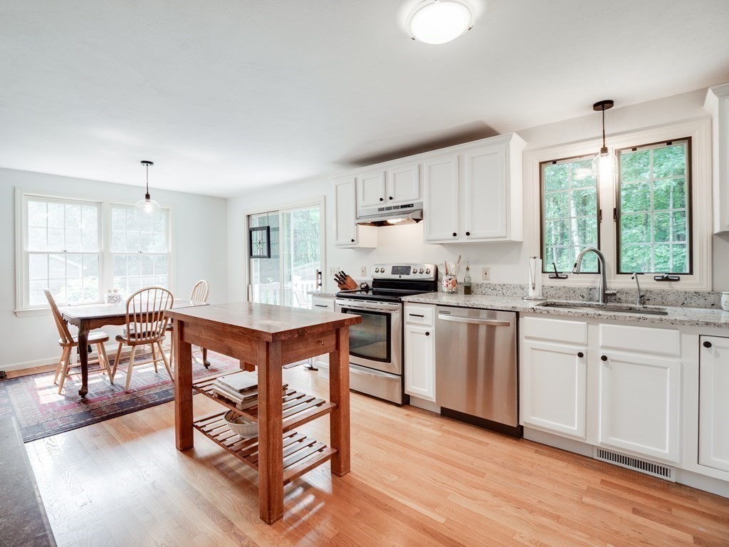 4 Crabtree Lane Shirley, MA 01464 - Photo 10 of 36 a kitchen with stainless steel appliances granite countertop a stove a sink dishwasher a microwave oven and a dining table with wooden floor