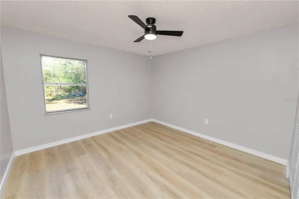 an empty room with wooden floor and ceiling fan