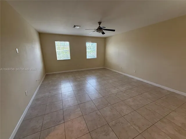 an empty room with wooden floor and a ceiling fan