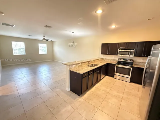 a kitchen with granite countertop a sink a counter top space cabinets and stainless steel appliances