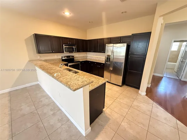 a kitchen with stainless steel appliances granite countertop a sink and a refrigerator