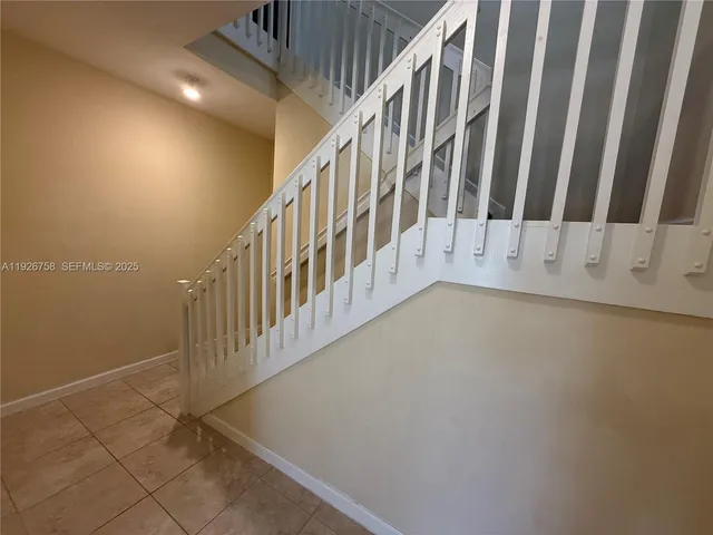 a view of staircase with railing and white walls