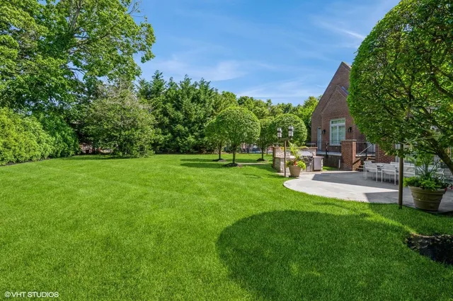 a view of a house with a big yard potted plants and large tree