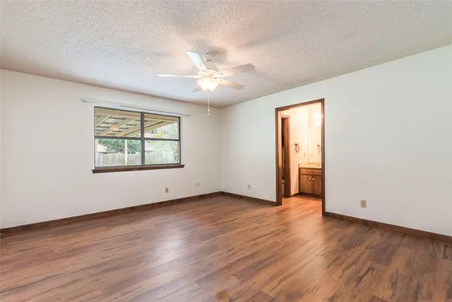 an empty room with wooden floor chandelier and windows