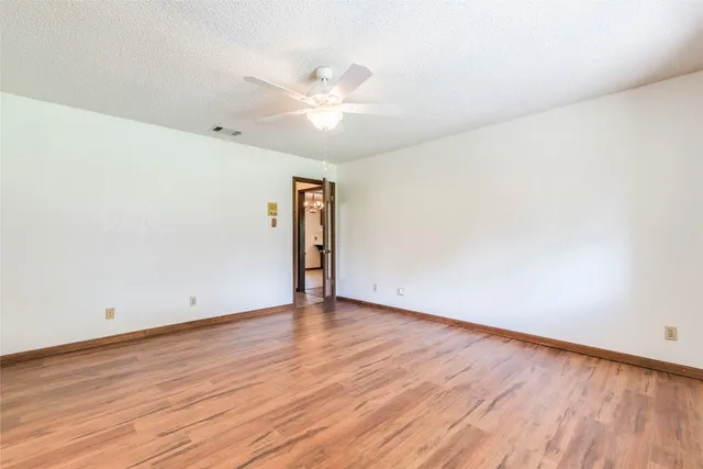 an empty room with wooden floor and fan