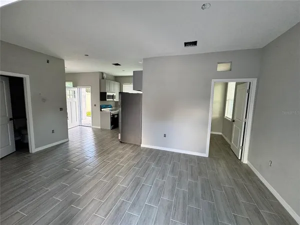 a view of an empty room with window and wooden floor