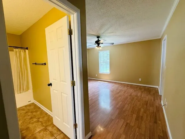 a view of a hallway with wooden floor and a bathroom