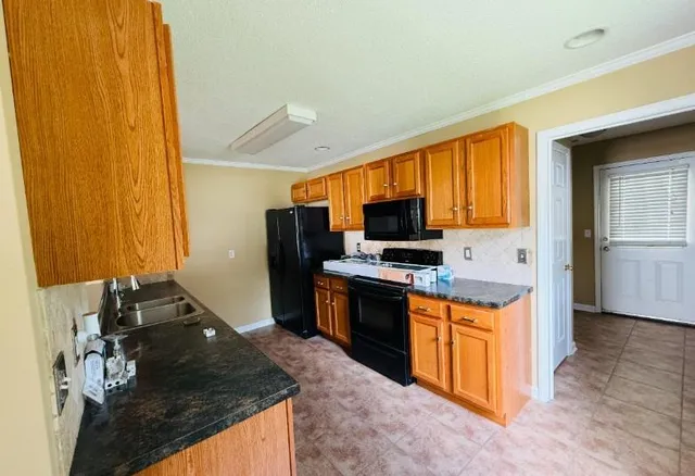a kitchen with stainless steel appliances granite countertop a stove refrigerator sink and microwave