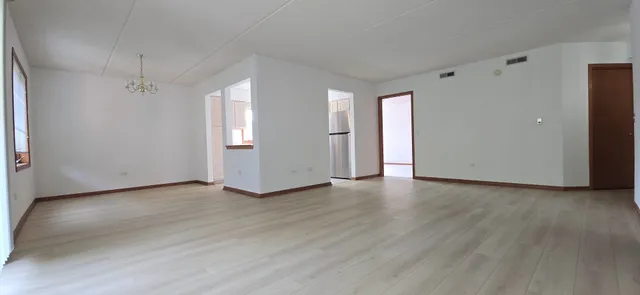 a view of an empty room with window and wooden floor
