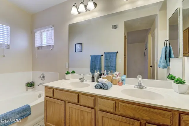 a bathroom with double vanity sinks a mirror and a bathtub