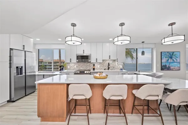 a kitchen with stainless steel appliances kitchen island granite countertop a stove a sink dishwasher and a refrigerator with wooden floor