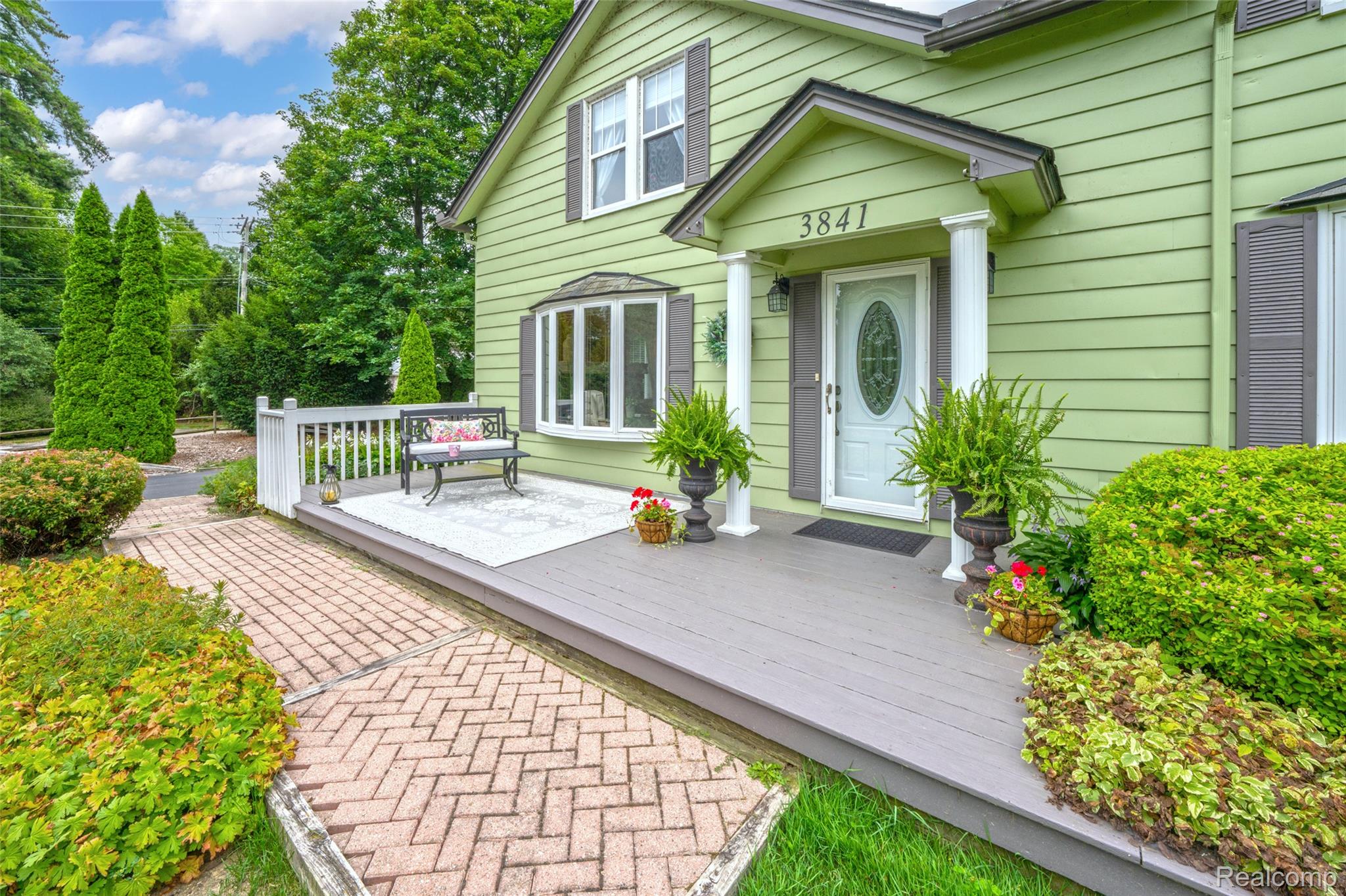 3841 Covert Road Waterford, MI 48328 - Photo 57 of 87 Front exterior featuring light green siding, a bay window, a white entry door with an oval glass insert, and a covered porch