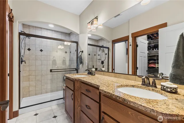 a bathroom with a granite countertop double vanity sink toilet mirror and shower