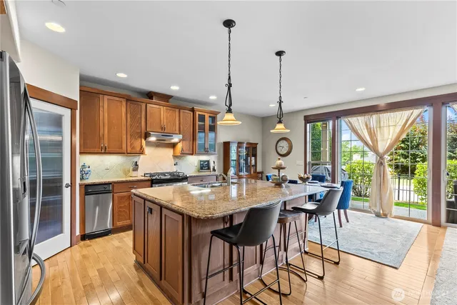 a kitchen with stainless steel appliances granite countertop table chairs and wooden floors