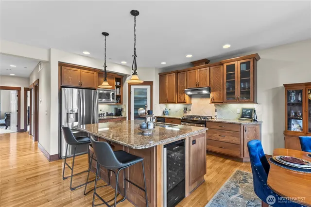 a kitchen with stainless steel appliances granite countertop stove top oven refrigerator dining table and chairs