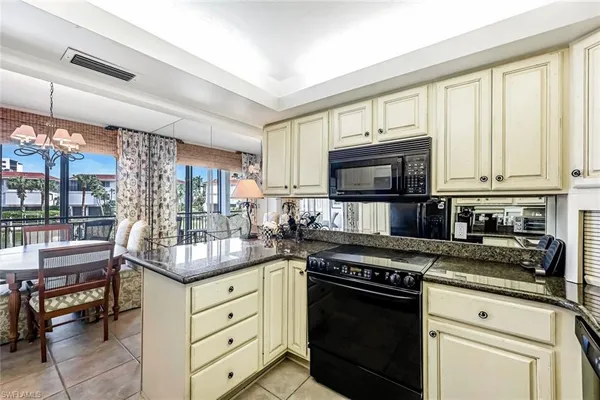 a kitchen with granite countertop a stove top oven microwave and cabinets