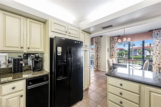 a kitchen with granite countertop a refrigerator and cabinets